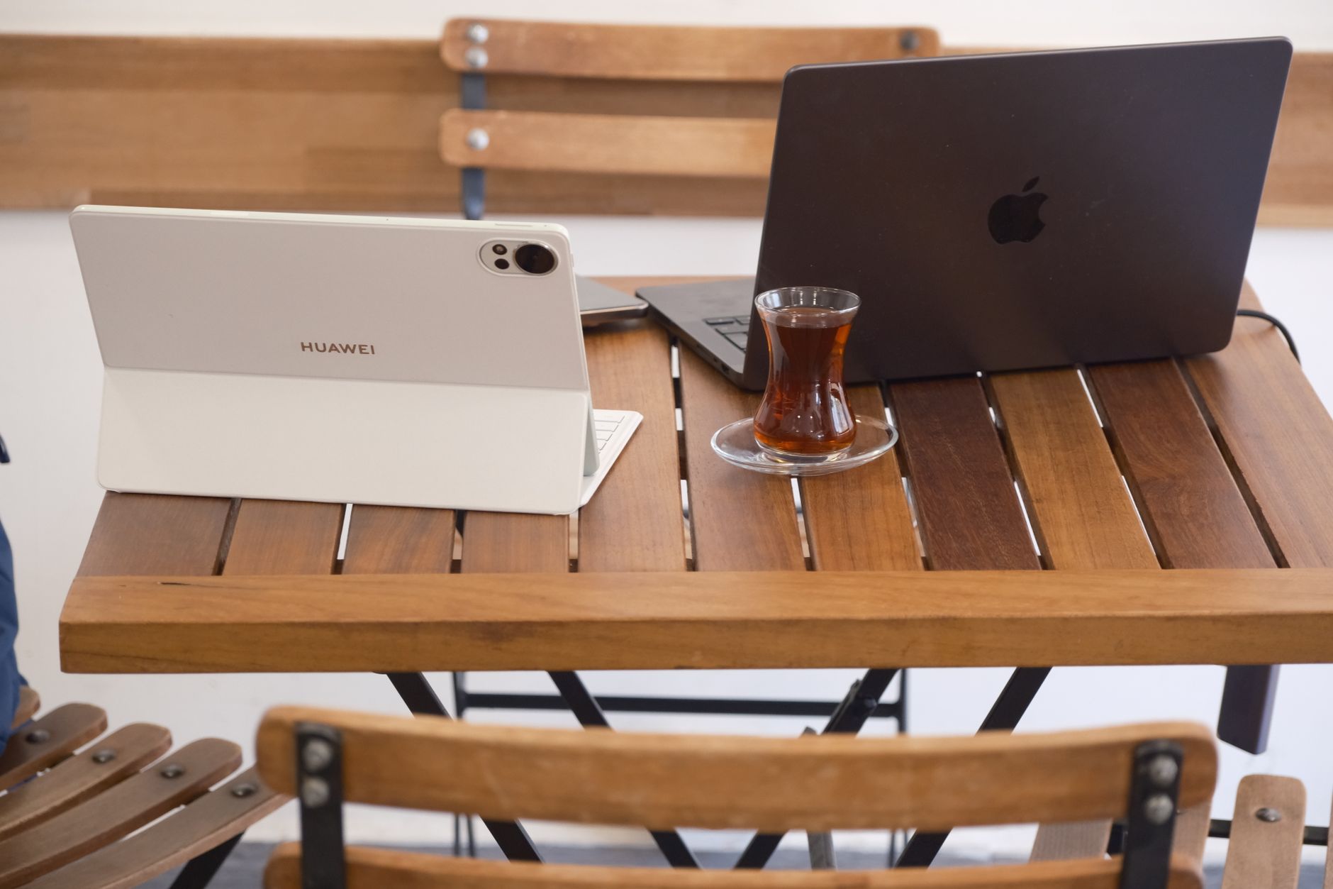 A cozy café workspace featuring a laptop with Turkish tea on a wooden table in İzmir, Türkiye.