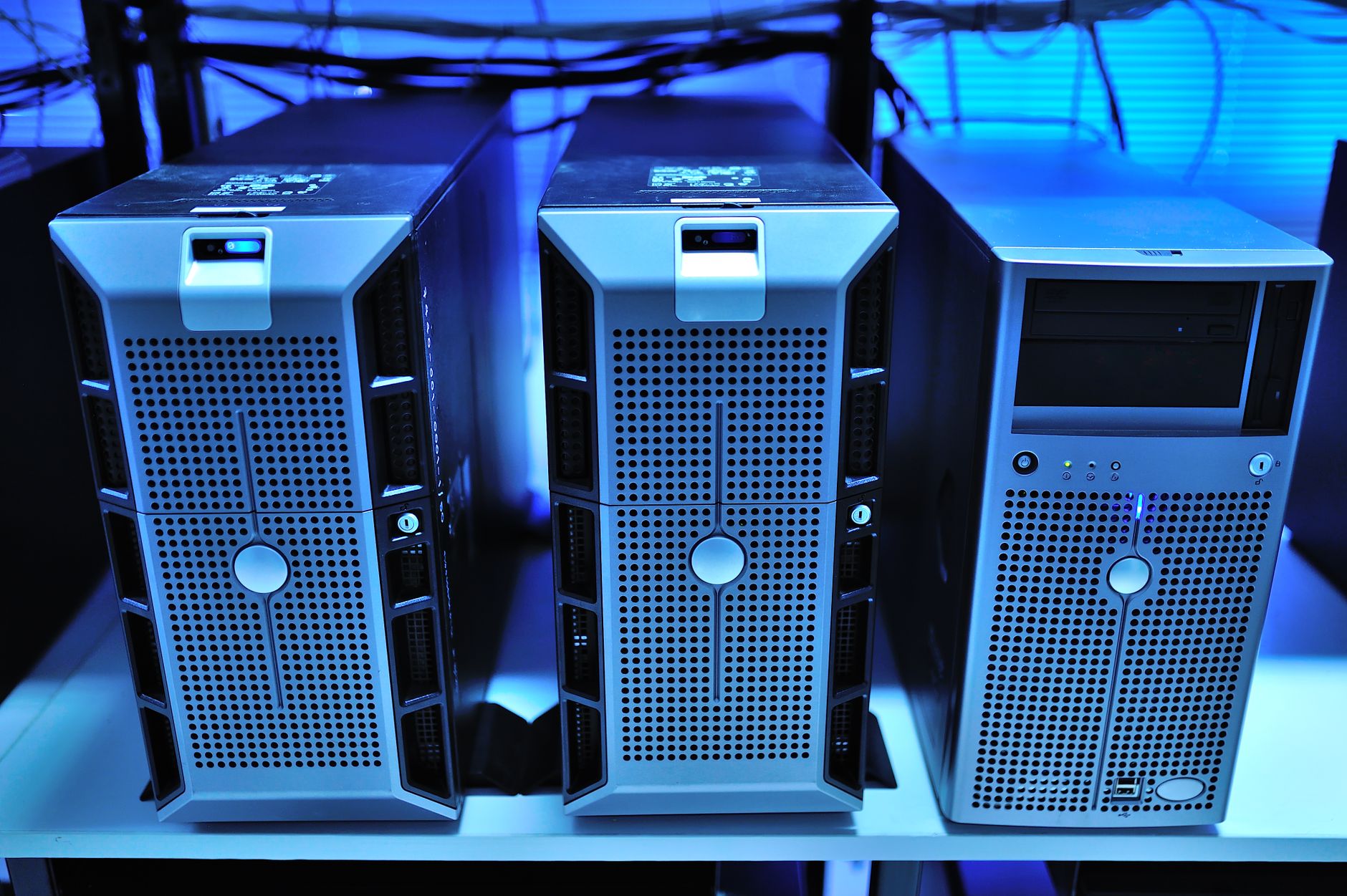Three compact servers in a blue-lit server rack.